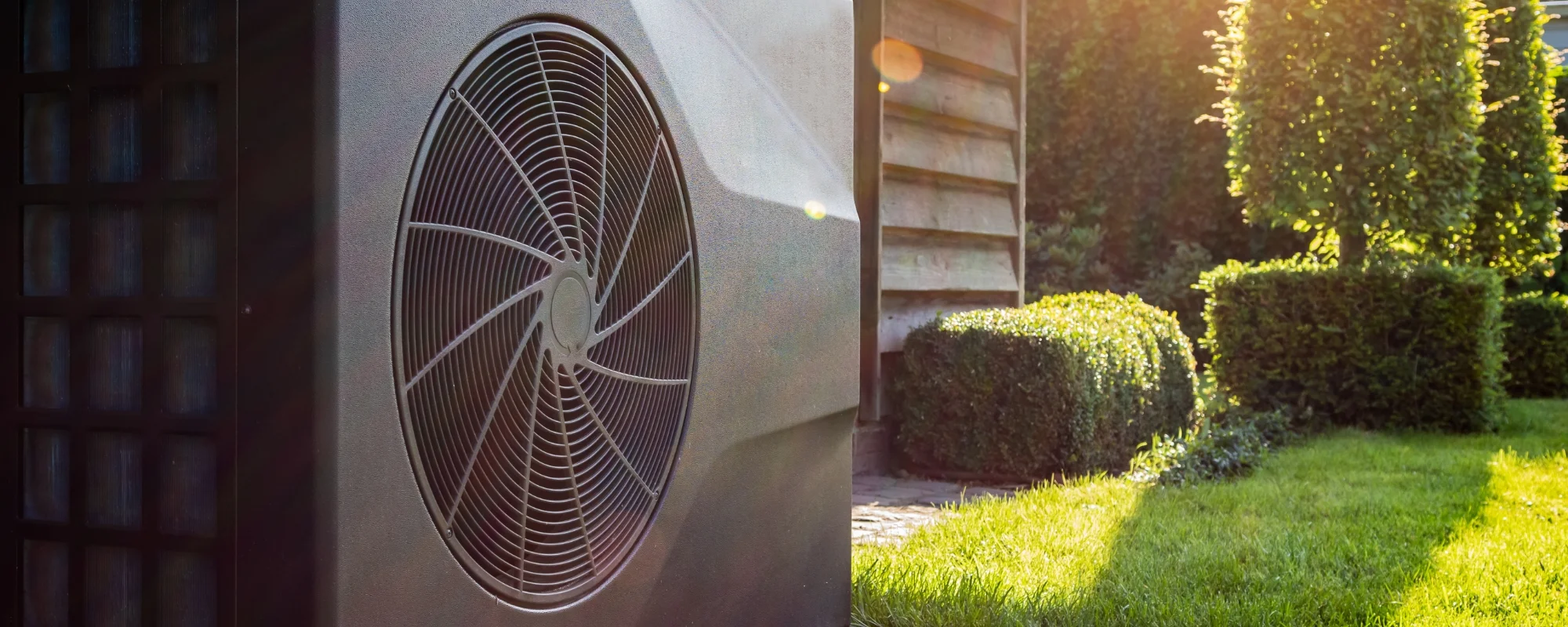 Heat pump outside a house in a sunny garden.