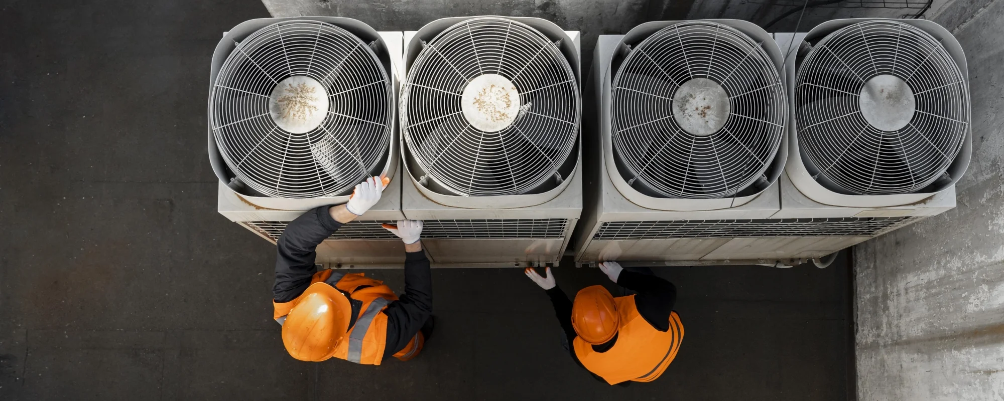Two workers inspecting air conditioning units.